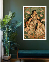 A framed art print depicting three women in traditional Indian sarees, hung on a dark green wall above a teal bench next to a potted palm plant.