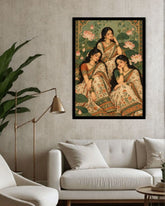 A framed art print depicting three women in traditional Indian attire seated among lotus flowers, displayed on a textured light gray wall above a white sofa in a modern living room setting.