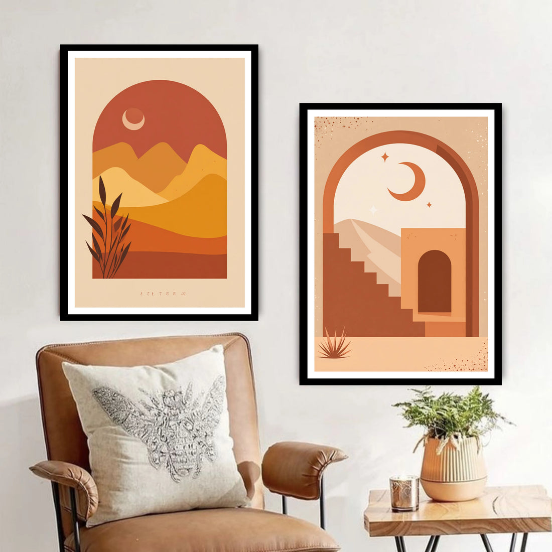 Two framed artworks on a wall above a chair with a pillow and a small table with a plant.