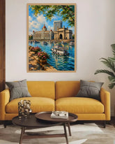 A framed canvas painting of a scenic city harbor with a historic building, boats, and lush green trees, displayed on a white wall above a yellow sofa in a modern living room setting.