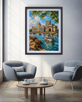 A framed colorful painting of a scenic harbor city with boats, buildings, and trees, displayed on a light gray wall above two modern gray armchairs and a round wooden coffee table.