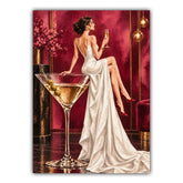 A vertical art print featuring a woman in a white satin gown seated beside a large martini glass with olives, set against a rich burgundy and gold interior. The artwork is shown centered on a light gray background.