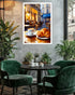 A framed wall art print depicting a cozy Parisian cafe scene with a croissant and coffee cup, displayed on a textured gray wall above a round black table with green velvet chairs in a styled interior.