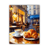 A square canvas art print depicting a Parisian cafe street scene at dusk, featuring a cup of coffee and croissants on a table in the foreground, with cafe seating and buildings in the background.