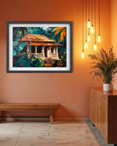A framed art print depicting a tropical house surrounded by lush green foliage, displayed on a terracotta-colored wall in a modern room setting with a wooden bench, cabinet, and hanging pendant lights.