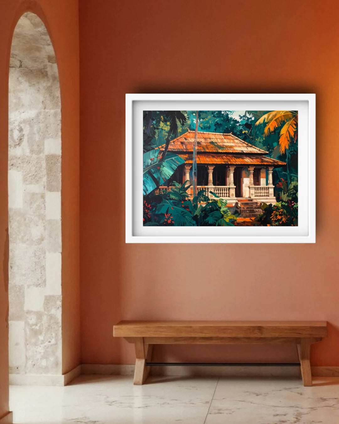 A framed art print depicting a tropical house surrounded by lush green foliage, hung on a terracotta-colored wall above a wooden bench.