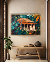 A framed tropical art print depicting a traditional house surrounded by lush green foliage and orange palm leaves, displayed on a beige wall above a wooden console table with decorative vases and books.