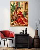 A framed art print depicting a woman in a red sari playing a stringed instrument, displayed on a light gray wall above a black side table in a styled room with a red chair and vases.