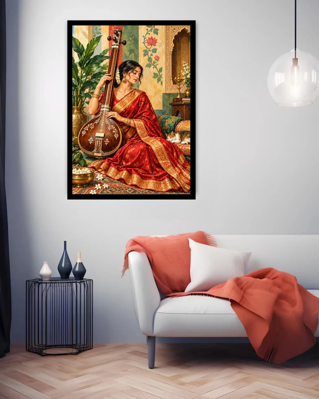 A framed art print depicting a woman in a red sari playing a stringed instrument, displayed on a light gray wall above a modern white sofa with a rust-orange throw blanket in a styled living room.