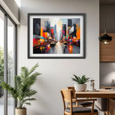 A framed abstract cityscape painting with vibrant multicolor streetlights and tall buildings, displayed on a light gray wall in a modern dining room setting.