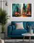 A framed abstract cityscape painting in teal, orange, black, and white hangs on a light gray wall above a blue sofa in a modern living room setting.