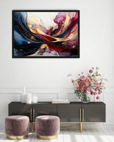 A framed abstract floral wall art print hangs above a dark gray console table in a styled room. The artwork features flowing brushstrokes of deep blue, burgundy red, gold, and pink on a white background.