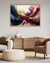 Abstract framed wall art hanging above a wooden cabinet in a modern living room. The artwork features flowing brushstrokes of deep blue, burgundy, magenta, gold, and cream on a light background.