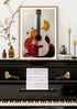 Framed abstract guitar artwork on a piano with sheet music underneath