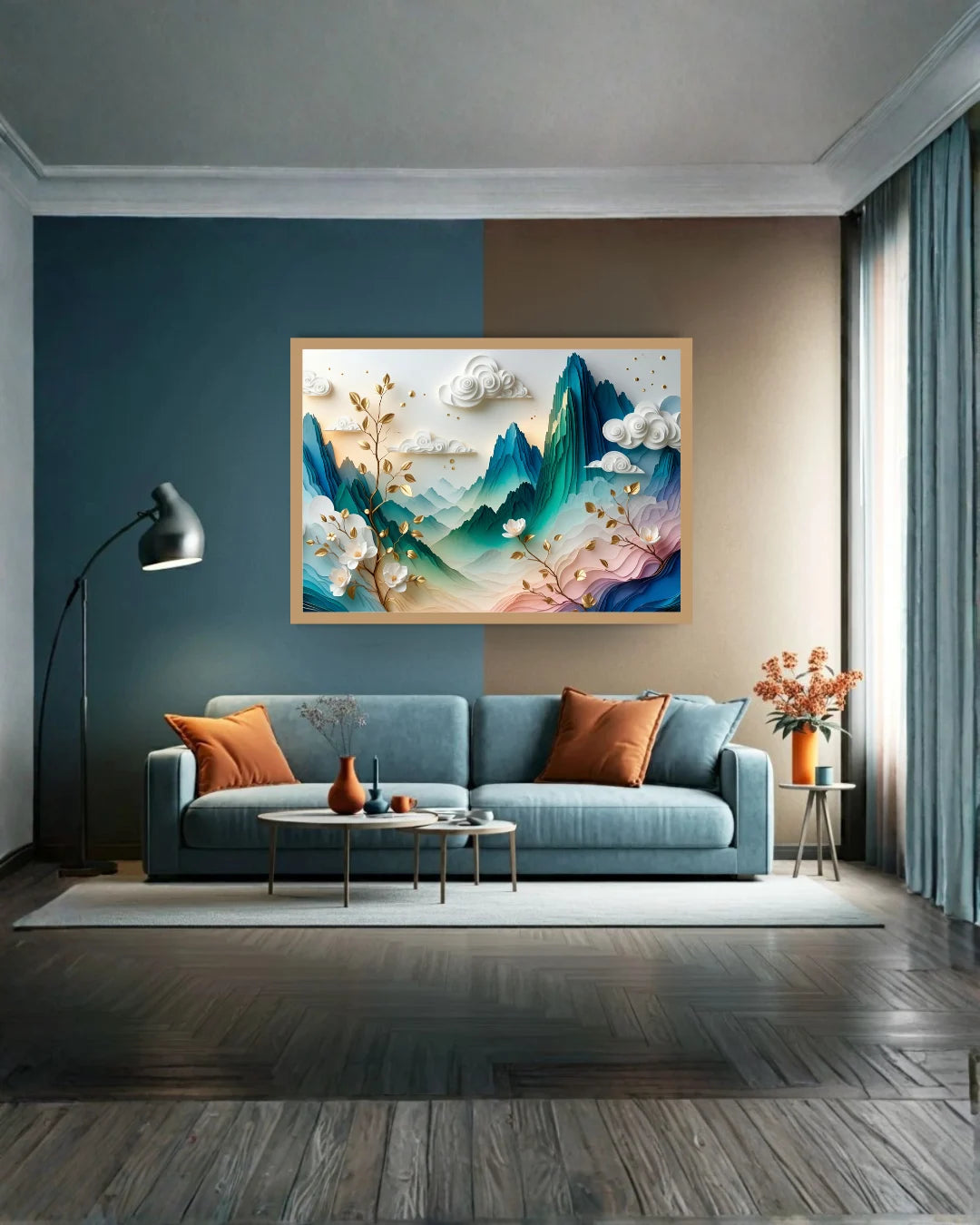 A framed landscape art print featuring blue and green mountains with white clouds and gold branches, displayed on a two-tone blue and beige wall above a blue sofa in a modern living room.