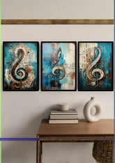Three framed abstract wall art prints featuring large treble clefs in blue, teal, beige, and black tones, displayed above a wooden console table with books and a white vase.