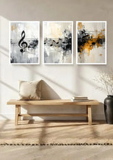 Three framed abstract wall art prints with musical notes hang above a light wood bench in a bright, modern room with a beige pillow, books, and a dark vase.