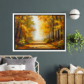 Framed painting of an autumn forest on a wall above a bed.