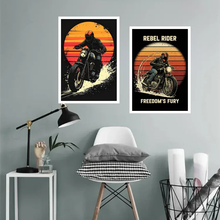 Two framed wall art prints featuring biker riders against a sunset are displayed on a light gray wall above a white chair in a styled room setting.