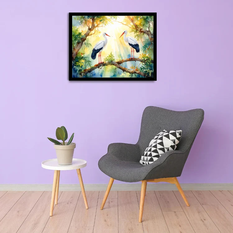 Framed artwork of two storks on a branch above a gray chair with a plant and pillow.