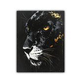 A square wall art print or canvas featuring a close-up portrait of a black panther with glowing amber eyes, white whiskers, and gold splatter details on a black background, shown against a light gray studio backdrop.