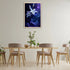 Blue abstract floral wall art frame displayed on a modern dining room wall with wooden table and chairs