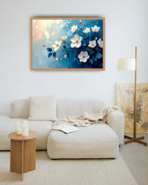 Blue floral wall art canvas displayed above a cream sofa in a modern living room
