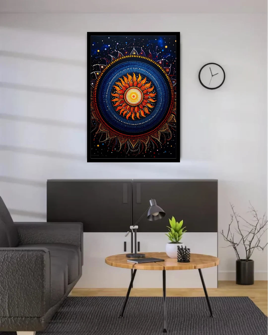 A framed square wall art print featuring a colorful mandala-style sun design hangs on a white wall above a modern gray cabinet in a styled living room setting.