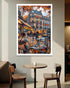 Framed artwork of a city street scene with people sitting at a table, displayed in a cafe.