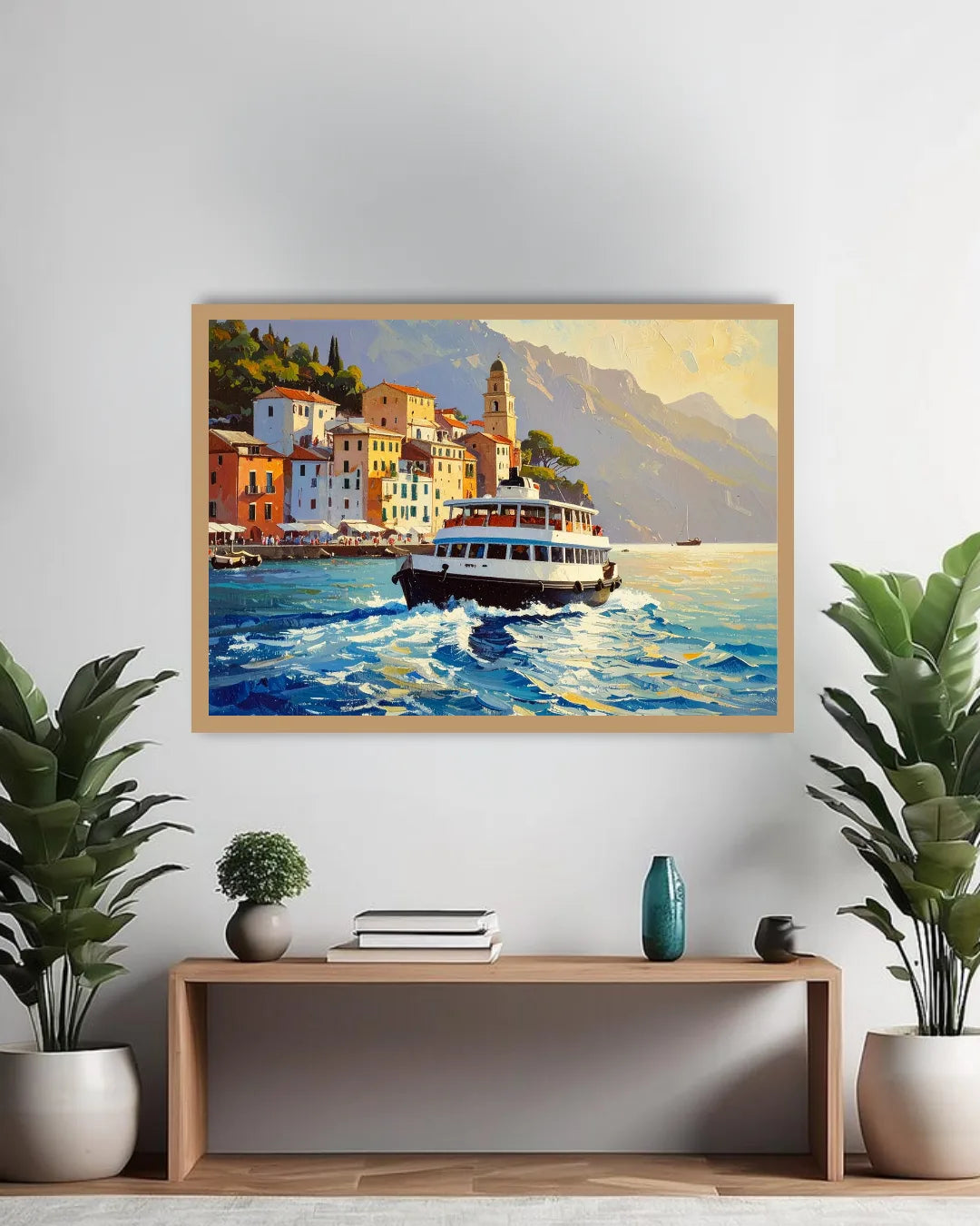 A framed canvas painting of a scenic coastal town with a ferry on the water, displayed on a light gray wall above a wooden console table with plants and decorative items.