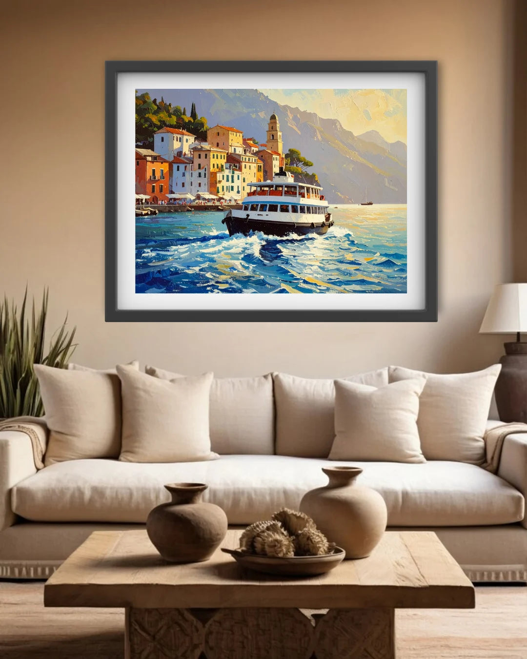 A framed art print depicting a scenic coastal town with a boat on the water, displayed on a beige wall above a modern white sofa in a living room setting.