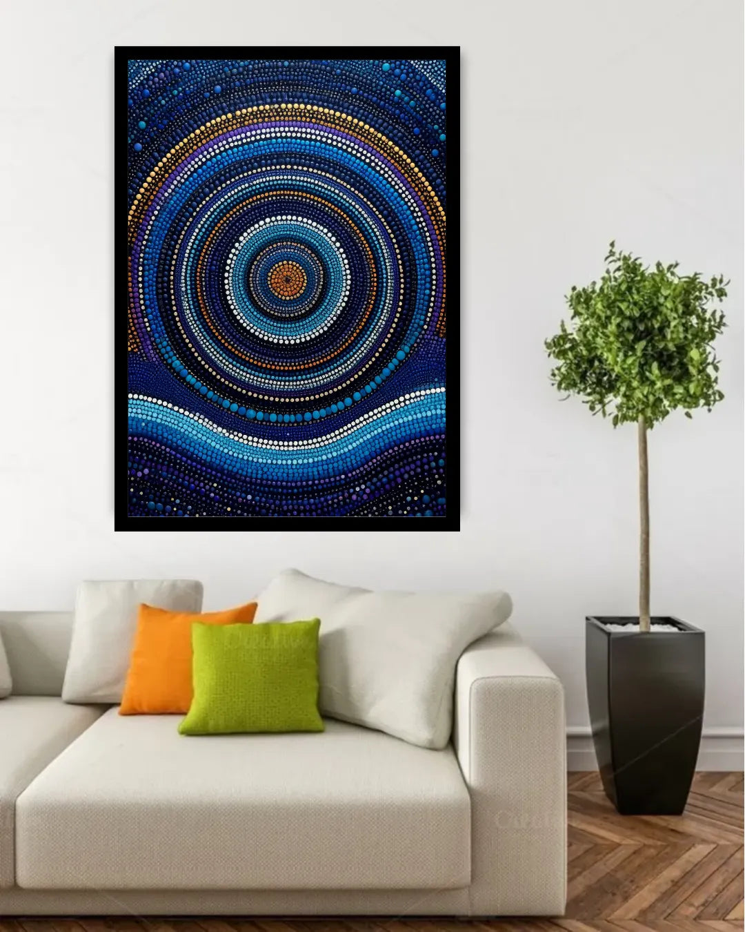 A framed abstract wall art print featuring concentric circular and wavy dot patterns in deep blue, navy, black, white, and small gold accents, displayed above a light beige sofa in a modern living room setting with decorative pillows and a potted tree.