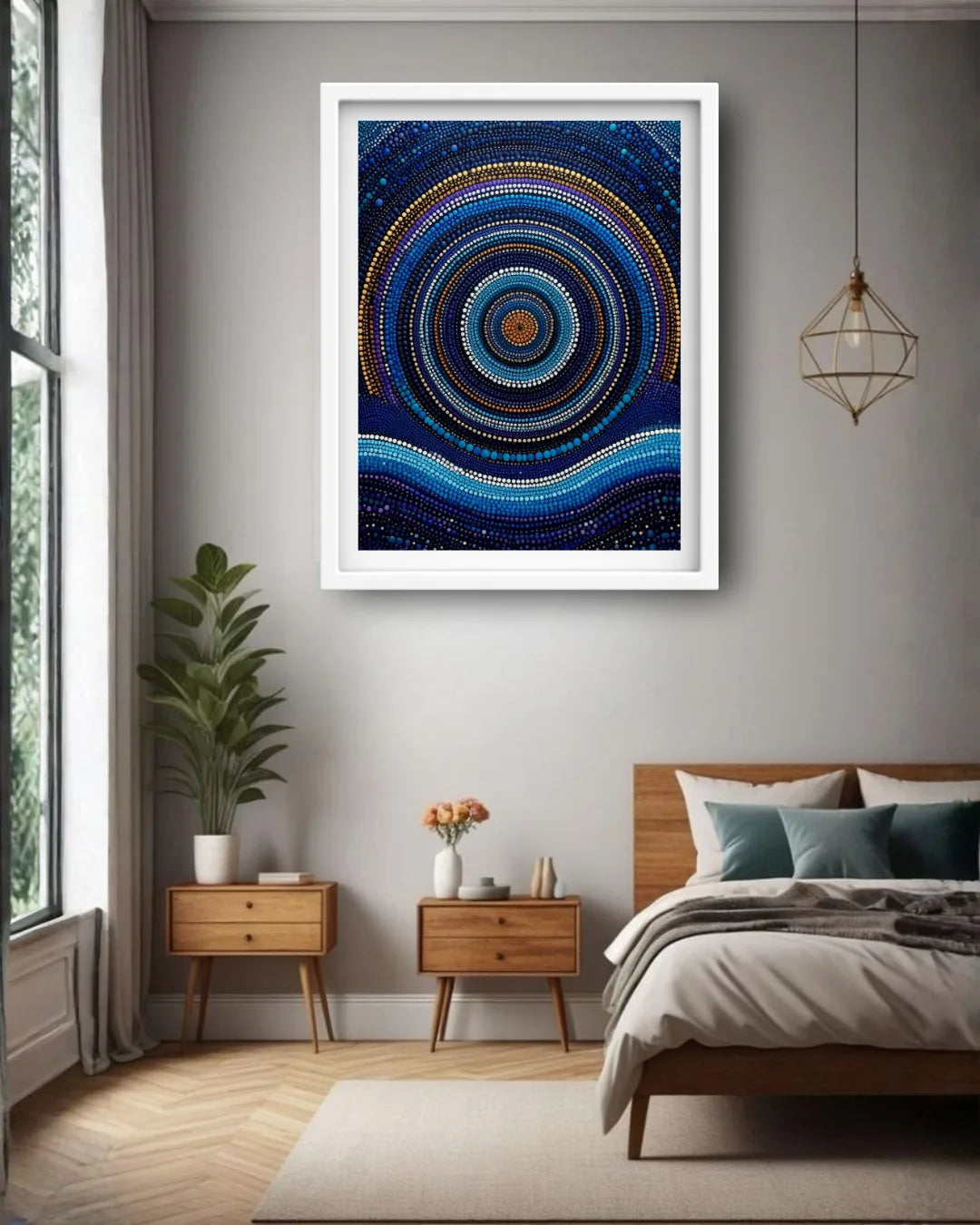 A framed abstract art print featuring concentric circles and dots in shades of blue, black, and gold, displayed on a gray wall in a modern bedroom setting.