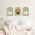 Three framed artworks on a wall above a bed with pink bedding.