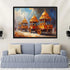 A framed painting of ornate golden chariots under a blue sky, displayed on a light gray wall above a blue sofa with cream pillows.