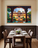 A framed canvas print of an Indian palace courtyard under arches, displayed on a beige wall above a wooden dining table set with white plates and chairs.