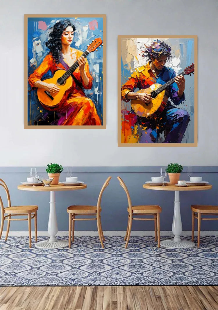 Two framed colorful paintings of women playing guitars hanging on a wall above two small dining tables with chairs in a styled interior room.