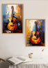 Two framed abstract paintings of acoustic guitars in warm orange, yellow, blue, and brown tones, displayed on a white wall above a table with an open book and a cup.