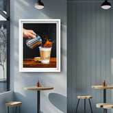 Framed artwork of a hand pouring coffee into a cup on a wall in a modern cafe setting.