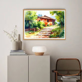 Framed landscape painting of a rustic house with a staircase on a wall above a cabinet.