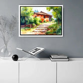Framed painting of a rustic house in nature on a wall above a white cabinet.