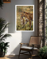 Framed artwork of leopards on a wall in a room with a chair and plants.