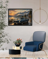A framed landscape art print depicting a blue classic car on a mountain road at sunset, displayed on a light gray wall in a modern living room setting with a blue armchair, side table, and hanging light.