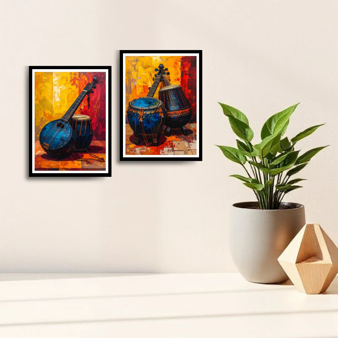 Two framed paintings of musical instruments on a wall with a plant and decorative object below.