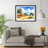Framed painting of a village scene above a gray sofa in a living room.