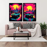 A pair of framed retro neon-style wall art prints hanging above a pink sofa in a styled living room. Each print shows a turquoise car driving through a colorful city street at sunset with a large yellow sun and pink sky.