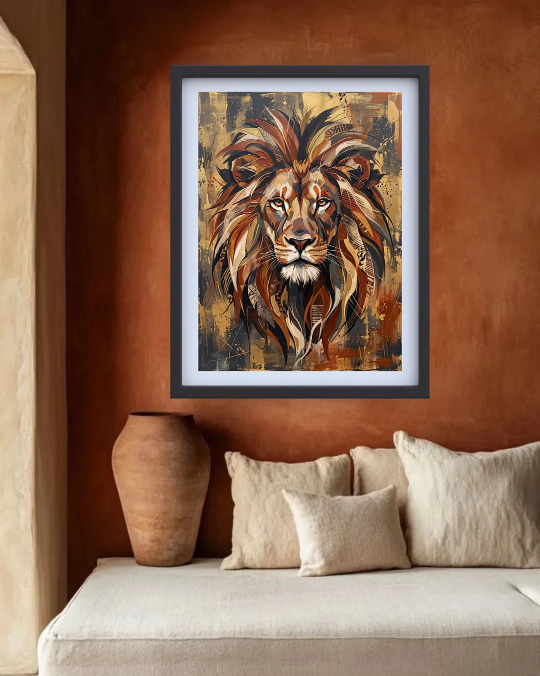 Framed wall art featuring a stylized lion portrait in warm brown, gold, and black tones, displayed above a beige sofa in a rustic interior with a terracotta wall and ceramic vase.