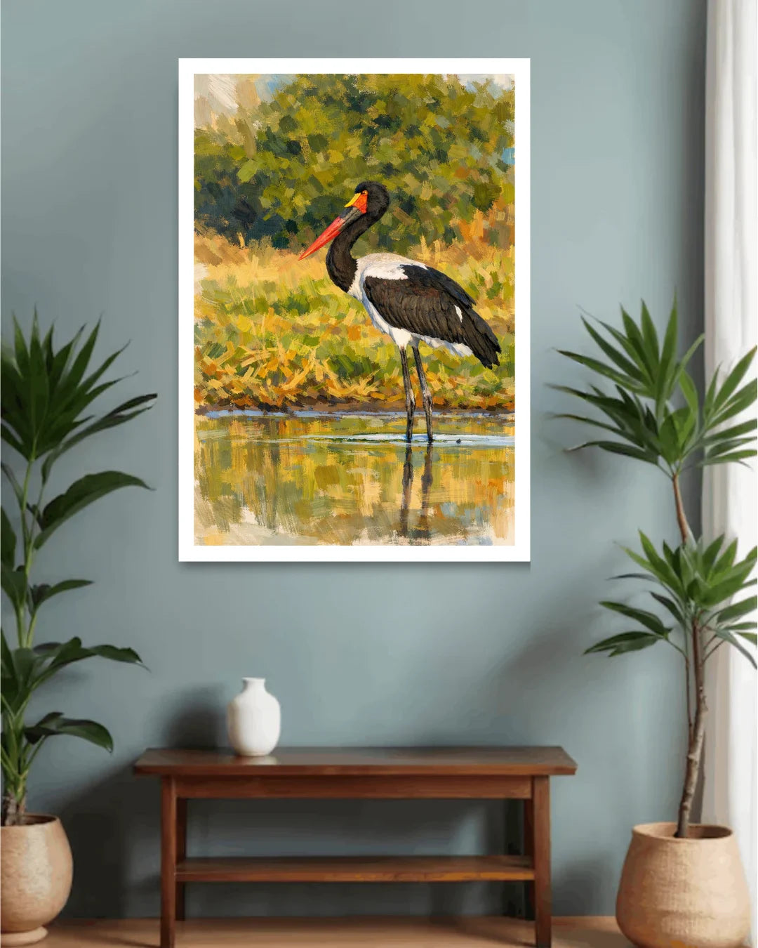 Framed painting of a stork by a lake on a wall above a wooden console table with decorative items.