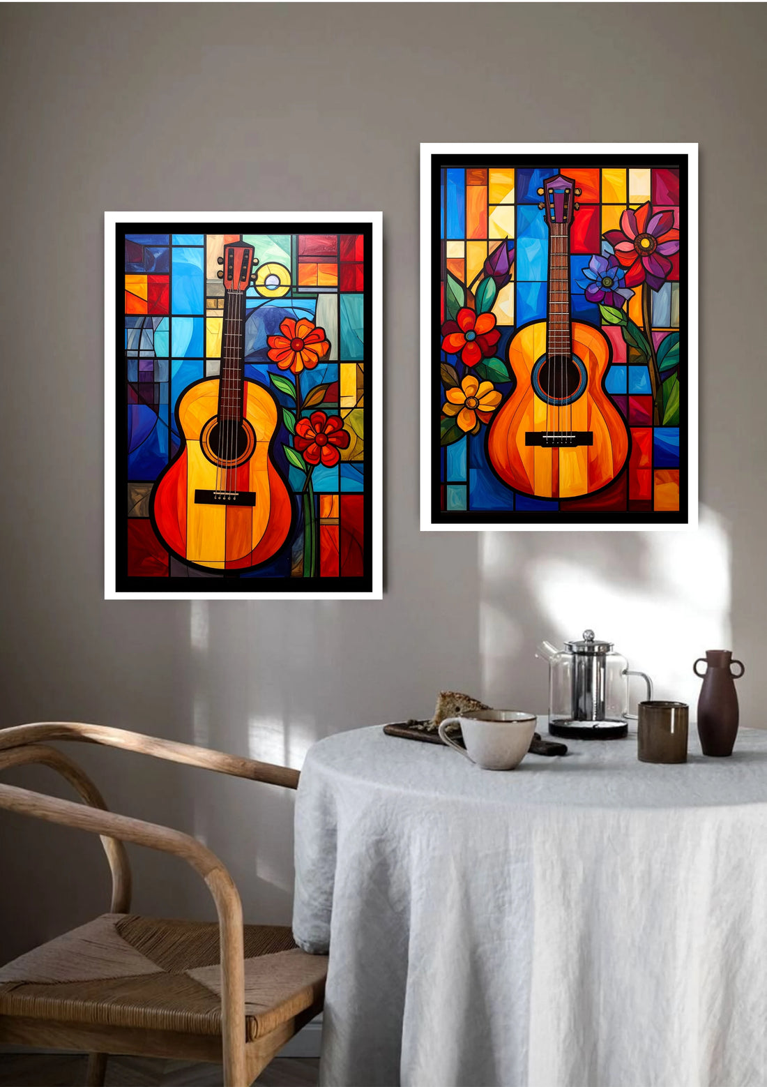 Two colorful abstract guitar paintings on a wall above a table with a chair.
