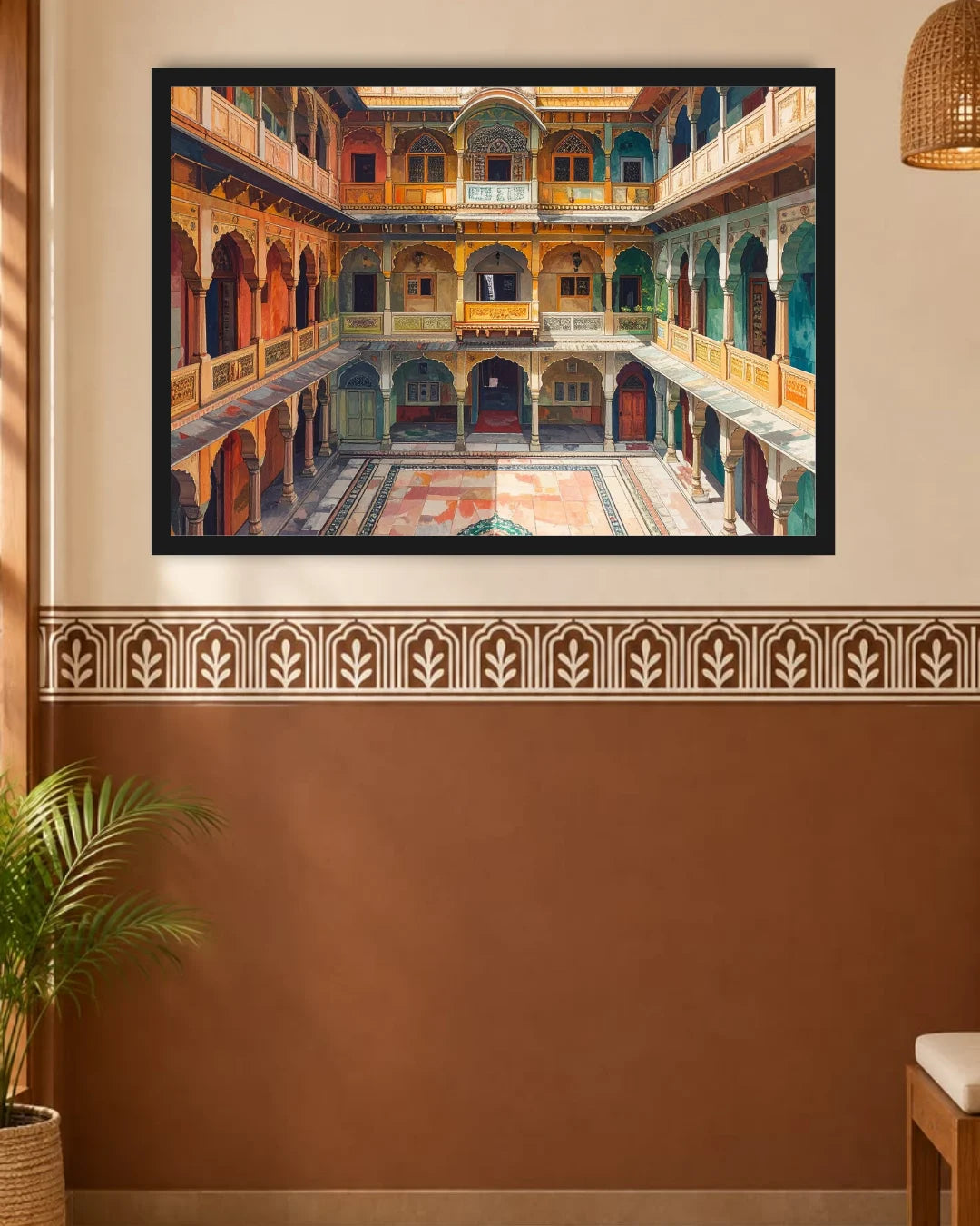 A framed art print depicting a traditional Indian palace courtyard with arches and balconies, displayed on a beige wall above a brown lower wall section with a decorative border.